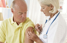 Ärztin sticht einem älteren Mann eine Spritze in den Oberarm