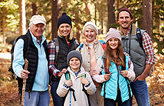 Drei Generationen von Wanderern vor einem herbstlichen Wald