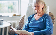 Frau mit Buch im Korbstuhl